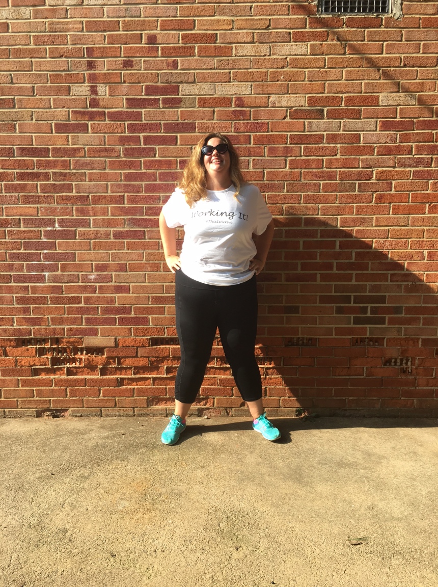 Jen Halter, blogger and fitness coach, standing in front of a brick wall on a sunny day.  She is wearing JunoActive plus size activewear.